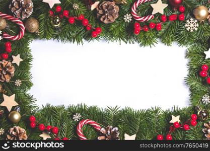 Christmas Border frame of tree branches on white background with copy space isolated, red and white decor, berries, stars, cones. Christmas frame of tree branches