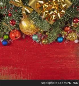 Christmas border with fir branches, conifer cones, christmas balls and golden christmas ornaments on rustic background, top view, copy space. Christmas decorating elements and ornament on rustic red wood table