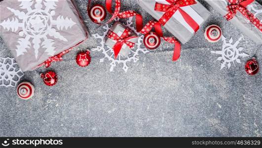 Christmas border with gift boxes, paper snowflakes, red ribbons and decorations, top view, banner