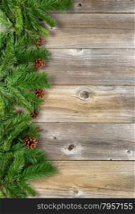 Christmas border with pine tree branches, and cones on rustic wooden boards. Layout in vertical format.