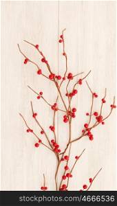 Christmas branch with red berries on a grey wooden background