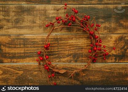 Christmas branch with red berries on a rustic wooden background