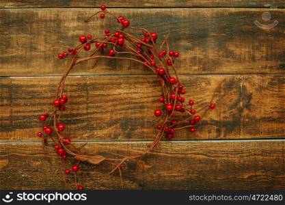 Christmas branch with red berries on a rustic wooden background
