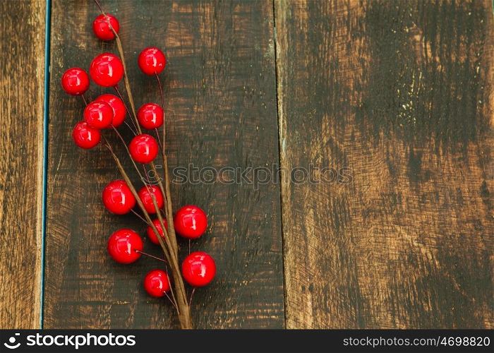 Christmas branch with red fruits on a wooden background