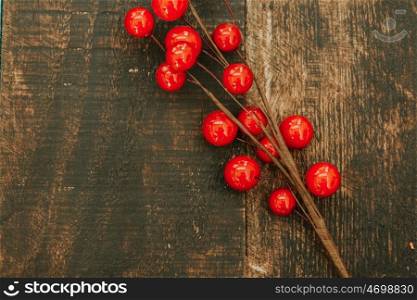 Christmas branch with red fruits on a wooden background