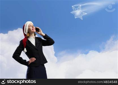Christmas calls. Woman in suit and Santa hat talking on mobile phone
