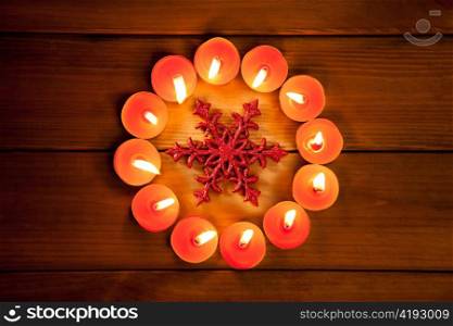 christmas candles circle over wood and red snowflake symbol