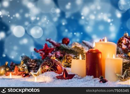 Christmas candles with traditional decorative stars , red baubles , pine cones and green branches on snow. Christmas candles with decoration