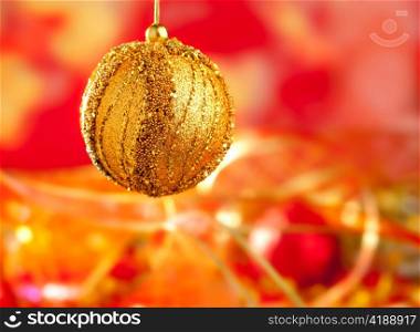 Christmas card of golden bauble and red blur background