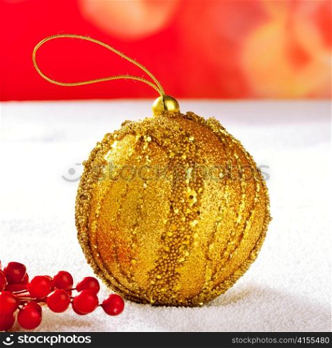 Christmas card of golden bauble berries on snow and red background