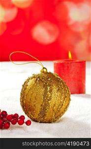 Christmas card of golden baubleand candle on snow