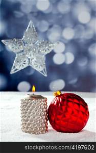 Christmas card of silver star bauble and candle on snow and blue background