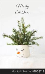 Christmas card snowy tree in a cup with the face of a sleeping snowman