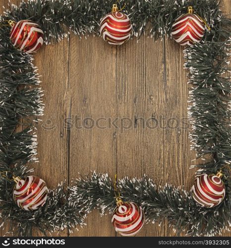 Christmas card with a fringe of branches of Christmas trees and festive toys on branches. Christmas card with a fringe of branches of Christmas trees and festive toys on branches on wooden background.