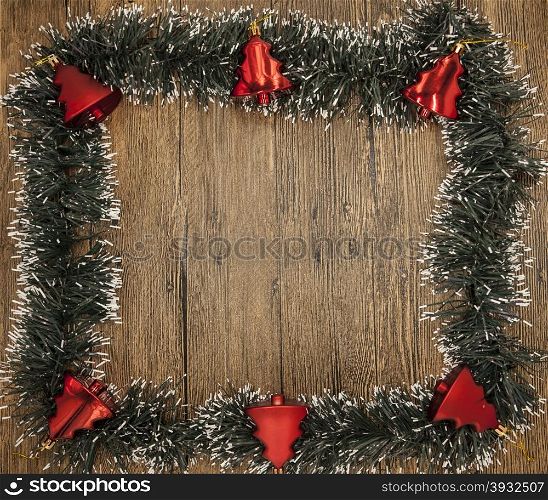Christmas card with a fringe of branches of Christmas trees and festive toys on branches. Christmas card with a fringe of branches of Christmas trees and festive toys on branches on wooden background.