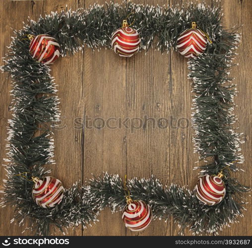 Christmas card with a fringe of branches of Christmas trees and festive toys on branches. Christmas card with a fringe of branches of Christmas trees and festive toys on branches on wooden background.