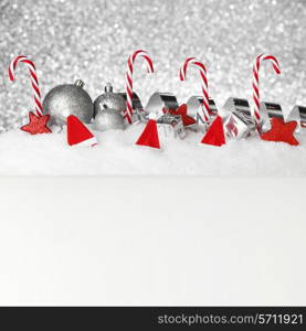 Christmas card with decorative baubles and candies on snow