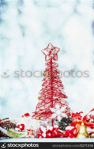 Christmas card with red tree, star and festive decoration on blue winter bokeh background, front view