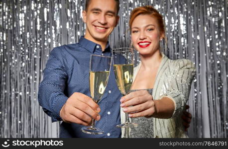 christmas, celebration and holidays concept - happy couple clinking champagne glasses at party. couple with champagne glasses at christmas party
