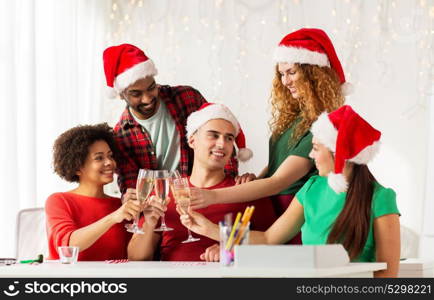 christmas, celebration and holidays concept - happy team in santa hats clinking glasses of non-alcoholic sparkling wine at corporate office party. happy team celebrating christmas at office party