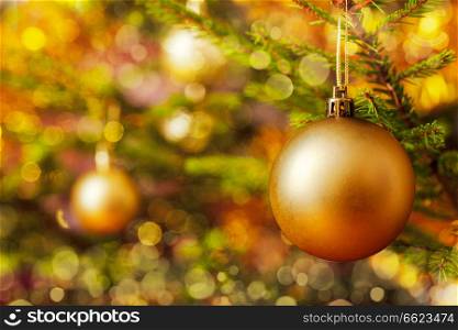 Christmas celebration holiday background - christmas-tree decoration bauble on decorated Christmas tree with defocused blurred lights bokeh and copyspalce. Decoration bauble on decorated Christmas tree