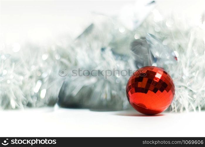 Christmas colorful ball on a background of silver tinsel garland. The object of the celebration with free space for text.