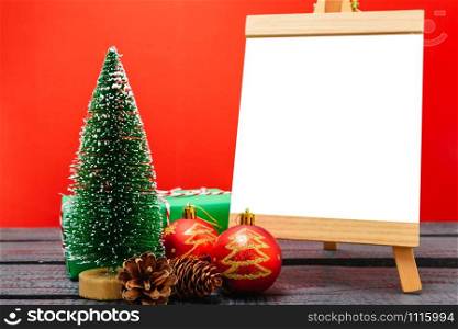 Christmas composition decorations, minimal green fir tree branches with snow and white chalkboard on red background. Merry Christmas concept. Copy space for text
