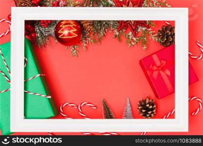 Christmas composition decorations, with white Photo frame square and fir tree branches on red background. Merry Christmas concept. Copy space for text