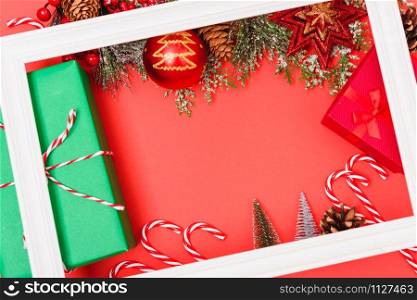 Christmas composition decorations, with white Photo frame square and fir tree branches on red background. Merry Christmas concept. Copy space for text