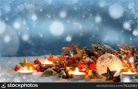 Christmas composition of colorful ornaments balls stars candles and fir tree branches on snow. Christmas composition on snow