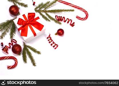 Christmas composition of green fir tree branch, Xmas gift and candy canes isolated on white background. Top view, flat lay. Copy space for text. Xmas gift and candy canes on white