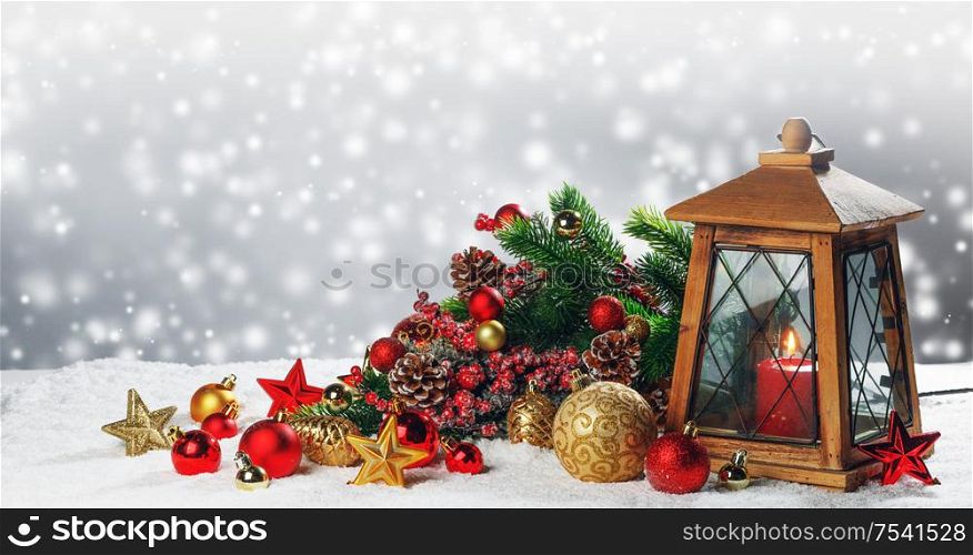 Christmas composition of lantern with candle inside , colorful ornaments , balls , stars and fir tree branches on snow. Christmas composition on snow