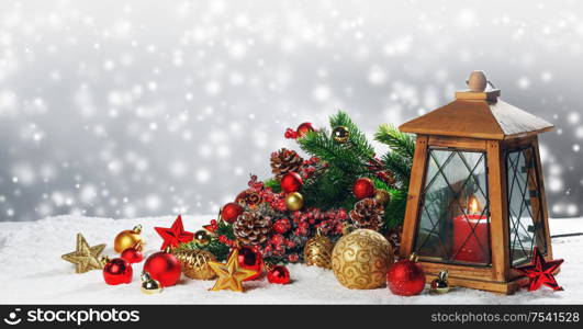 Christmas composition of lantern with candle inside , colorful ornaments , balls , stars and fir tree branches on snow. Christmas composition on snow