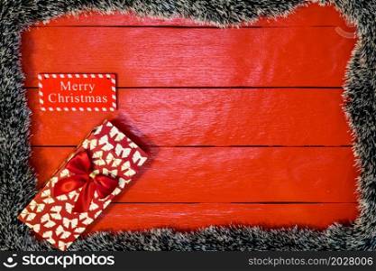 Christmas composition on red wooden board with Christmas garland and decorations. Creative composition with border and copy space, top view, flat lay. Christmas frame.