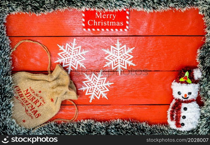 Christmas composition on red wooden board with Christmas garland and decorations. Creative composition with border and copy space, top view, flat lay. Christmas frame.