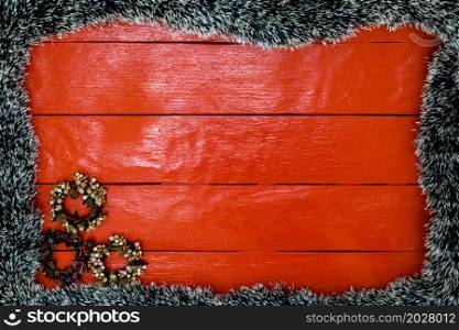 Christmas composition on red wooden board with Christmas garland and decorations. Creative composition with border and copy space, top view, flat lay. Christmas frame.