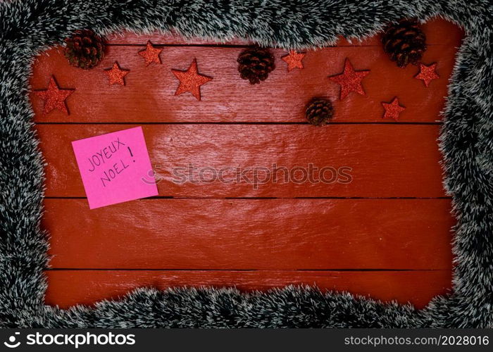 Christmas composition on red wooden board with Christmas garland and decorations. Creative composition with border and copy space, top view, flat lay. Christmas frame.