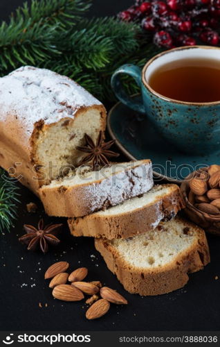Christmas composition with a cup of tea, sliced cake and spruce branches on a dark background