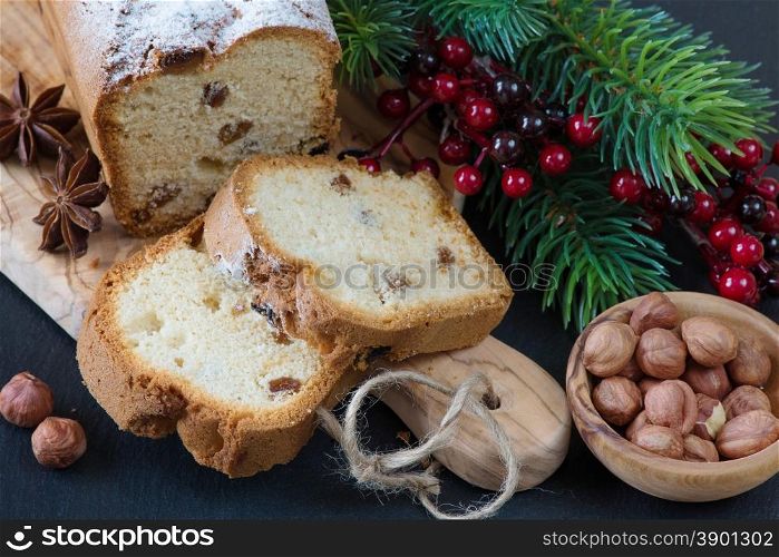 Christmas composition with a sliced cake and spruce branches on a wooden cutting board