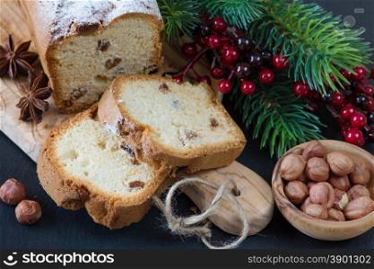 Christmas composition with a sliced cake and spruce branches on a wooden cutting board