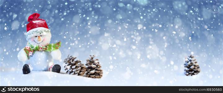 Christmas Concept: Cute Snowman Sitting with Pine Cones on the Blue and White Background with Snow