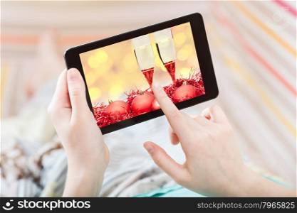 Christmas concept - woman in living room touches screen of tablet pc with Xmas still life on screen
