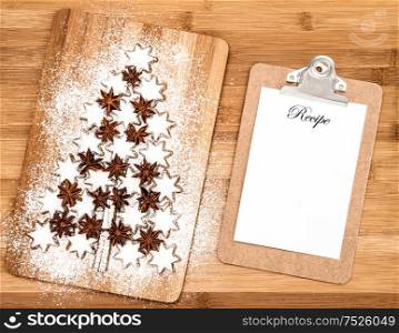 Christmas cookie cinnamon stars and notice board for recipe on wooden background. Christmas tree shaped cookies