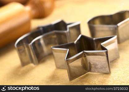 Christmas cookie cutters and rolling pin on dough (Selective Focus, Focus on the two front edges of the star-shaped cutter)