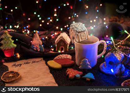 Christmas cookies and cup of tea on daark color bokeh lights background. Christmas cookies and cup of tea