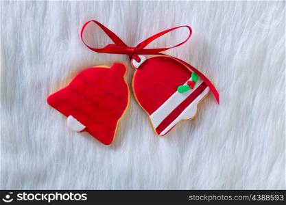 Christmas cookies Xmas red bell shape and ribbon on white fur background