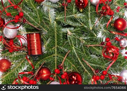 Christmas copmosition of fir tree branch and red decorations balls baubles pine ribbons background. Christmas fir and decorations