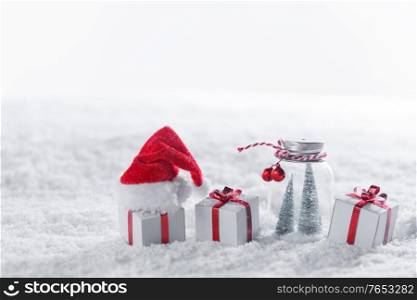 Christmas decor in snow gifts with red bows, Santa Claus hat, white copy space for text. Christmas decor in snow