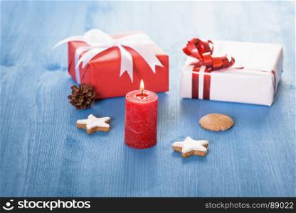 Christmas decor with small gift boxes, gingerbread cookies, and a lit red candle