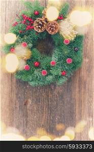 christmas decorated evergreen wreath on aged wooden background, retro toned